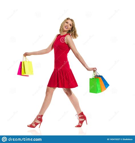 Happy Woman In Red Dress And High Heels Is Walking And Holding Colorful