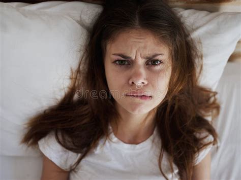 Woman With An Angry Expression Bites Her Lip While Lying In Bed Top