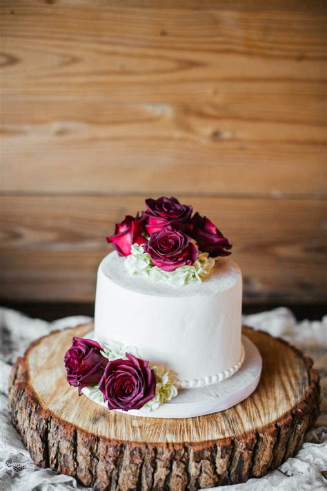 Round Single Tier Wedding Cake With Burgundy Roses On Natural Wood Tree