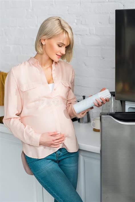 blonde pregnant woman looking at can with whipped cream while holding belly stock image image