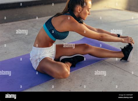 joven mujer en ropa deportiva fitness el estiramiento de la pierna en el exterior mujeres