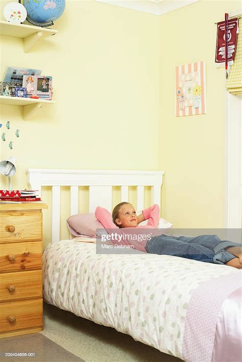 Girl Lying On Bed Looking Up Hands Behind Head Legs Crossed At Ankles