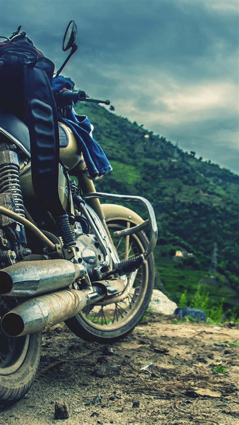 Download A Motorcycle Parked On A Dirt Road Wallpaper