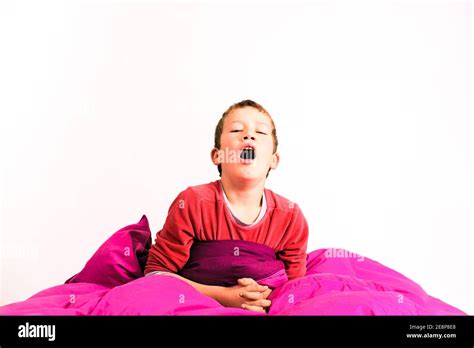 Adorable Blond Boy Yawning Just Woken Up In His Bed Isolated On White