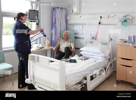 A Nurse Talks To An Elderly Patient In A Modern Uk Hospital Ward Both