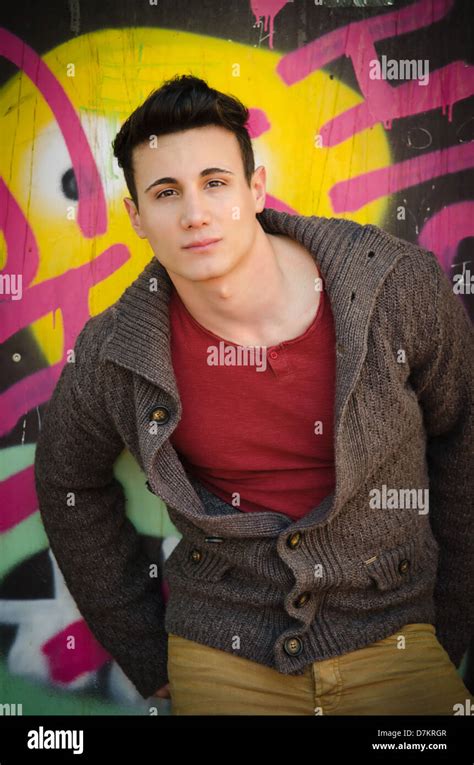 Attractive Young Man Standing Outdoors In Front Of Graffiti Covered