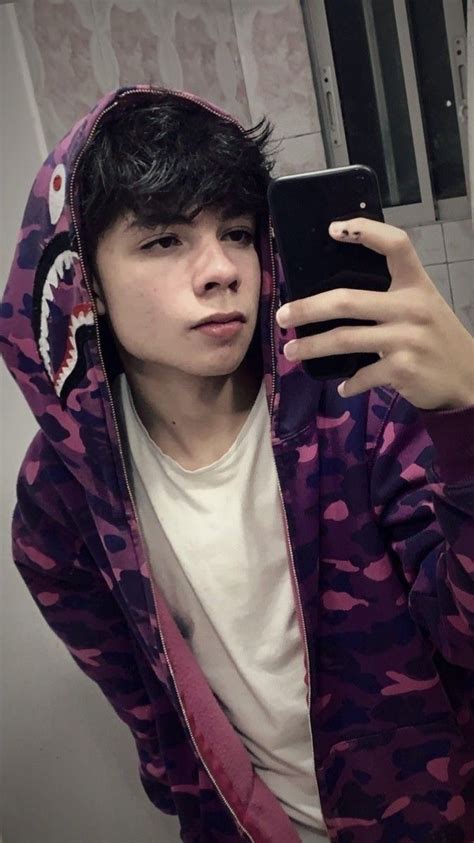A Young Man Taking A Selfie With His Phone In A Bathroom Mirror While Wearing A Purple Camo Hoodie