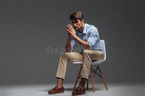 Thoughtful Handsome Young Man Sitting On Chair And Looking Away Stock