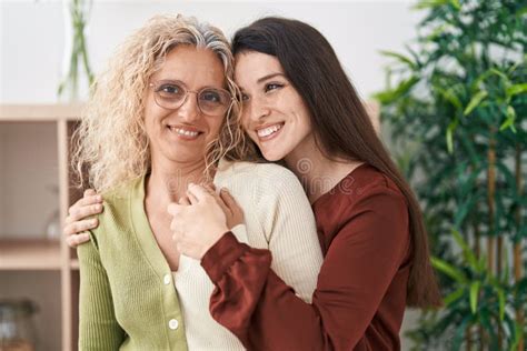 Two Women Mother And Daughter Hugging Each Other Standing At Home Stock