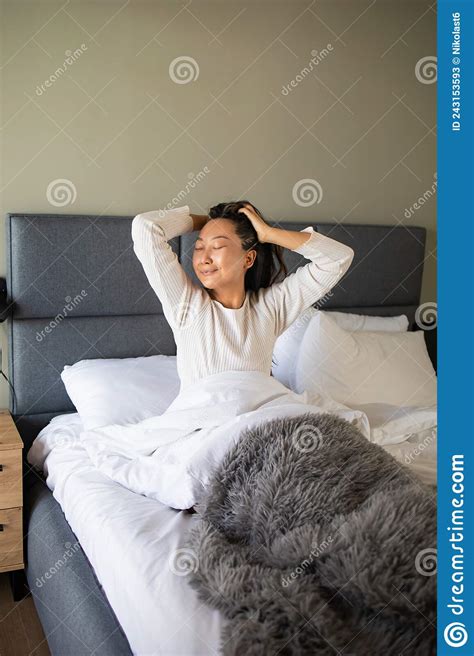 Beautiful Asian Woman Wakes Up In Her Bed In The Bedroom She Stretches And Smiles Stock Image