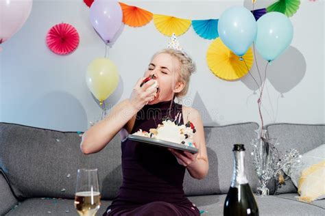 Woman In Festive Dress And Party Cap Eating Birthday Cake With Her