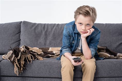 Bored Kid Boy Sitting On Sofa And Using Remote Control Stock Image