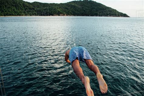 Rear View Of Man Diving Into Sea Stock Photo Dissolve
