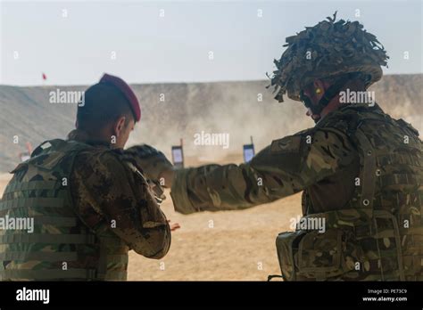 A British Soldier Assisting Task Group Taji Helps An Iraqi Soldier
