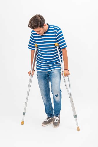 Disabled Young Man Trying To Walk With Crutches Over White Background