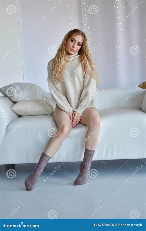 La Fille Sexy Est Assis Dans Des Poses Rotiques Avec Distant Large De Jambes Sur Le Sofa Dans