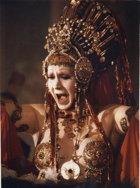 A Woman In Costume With Her Mouth Open And Eyes Wide Open Wearing Gold
