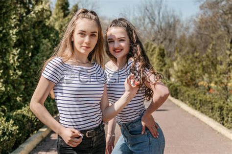 Two Smiling Young Female Girl Friends Having Fun In Park Stock Photo