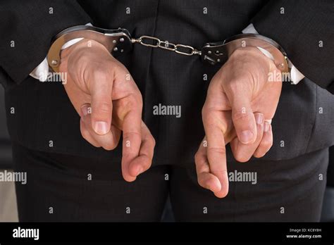 Close Up Of Businessman Avec Des Menottes Et Des Doigts Croisés Les Doigts Croisés Comme Un