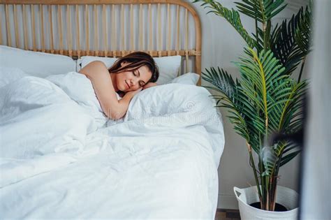 Young Calm Woman Sleeping Well Alone In Comfortable Bed Lady With Happy Face And Smile In Light