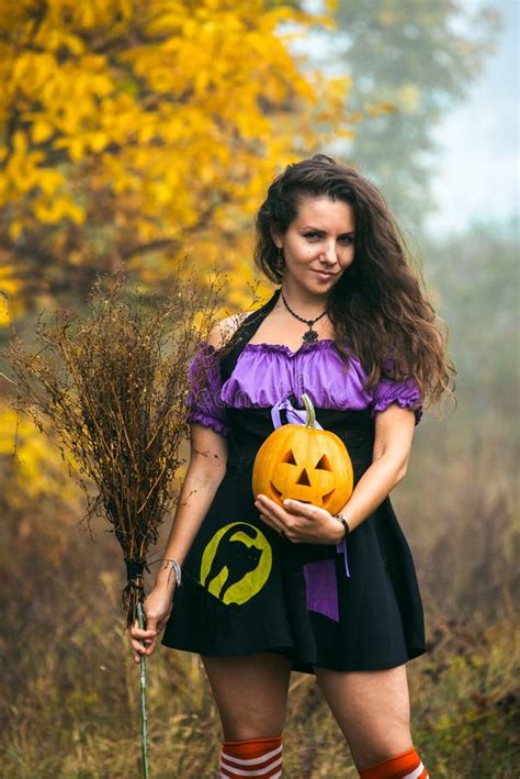 Young Woman In Halloween Witch Costume In The Autumn Forest With Yellow