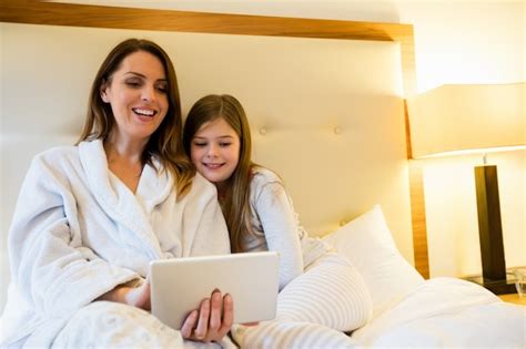 free photo mother and daughter using digital tablet in bedroom
