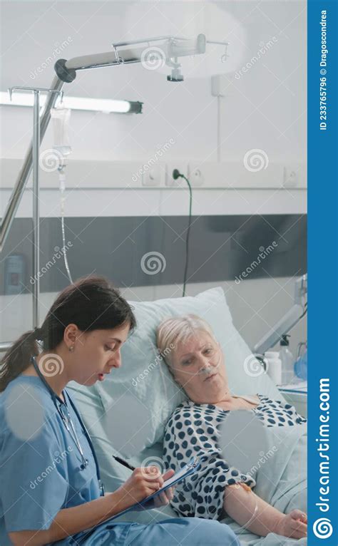Medical Assistant Doing Checkup Visit For Patient In Hospital Ward Bed