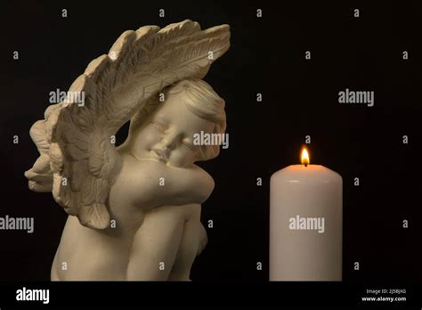 Angel with burning candle against black background. Moment of sorrow at