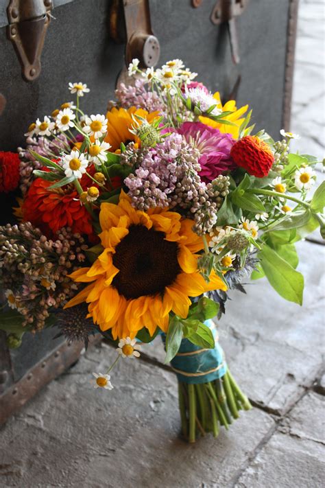 A Bouquet Of Sunflowers And Other Flowers Sits In Front Of An Old Trunk
