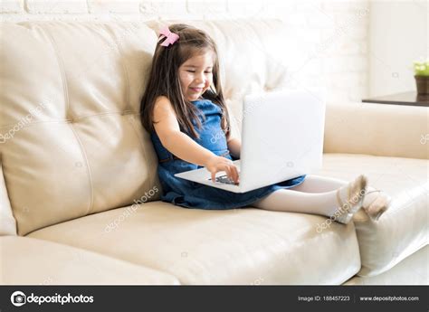 Petite Fille Assise Sur Canapé Avec Ordinateur Portable Dans Salon