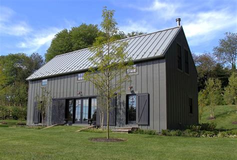 A Small House With A Metal Roof In The Middle Of A Grassy Area Next To