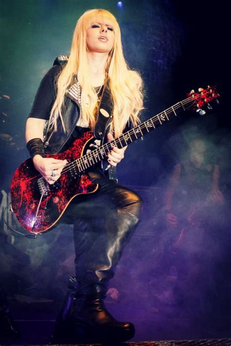 A Woman With Long Blonde Hair Playing An Electric Guitar