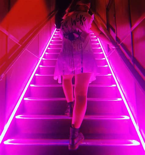 a woman is walking down some stairs with neon lights