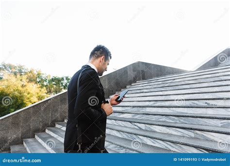 Handsome Young Businessman Walking Outdoors At The Street Using Mobile