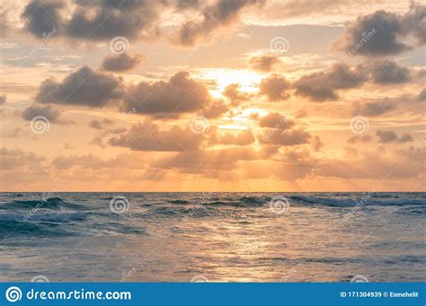 Sunrise Seascape With Colorful Golden Orange Clouds And Soft Blue Waves