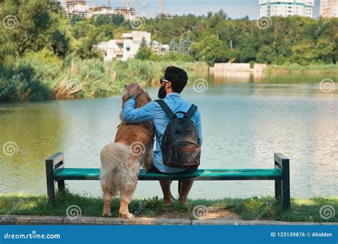Young Man Sitting With His Dog On The Chair In The Park Enjoyin Stock