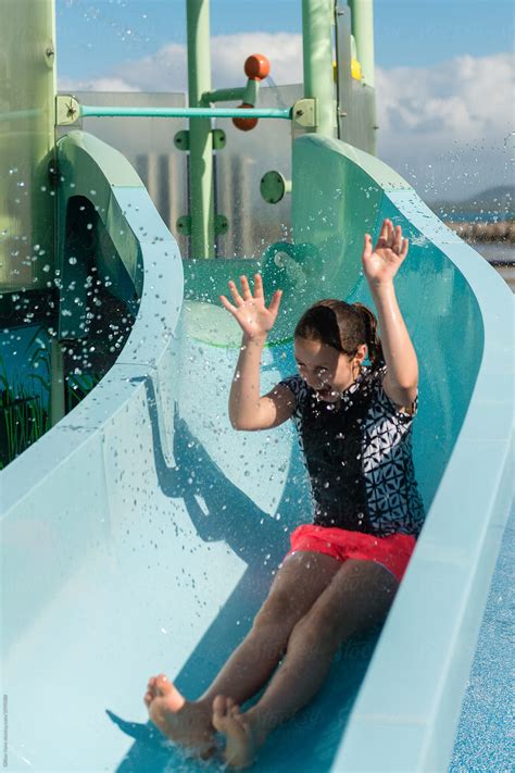 Girl At A Waterpark Being Splashed With Water On A Slide By Stocksy