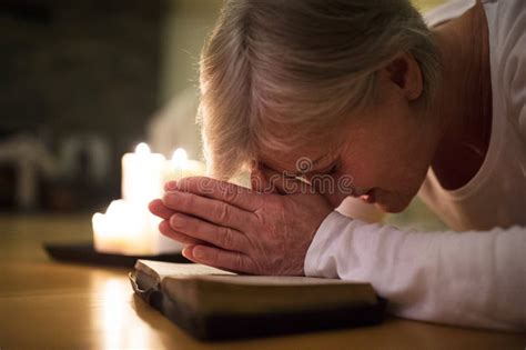 Senior Woman Praying Hands Clasped Together On Her Bible Stock Image