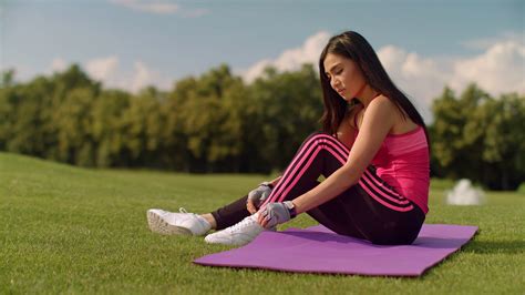 asian woman tying laces on her sneakers cute girl stretching on yoga mat and tying shoelaces in
