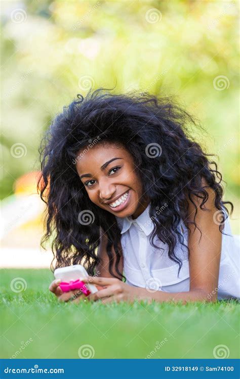 fille noire adolescente à l aide d un téléphone se trouvant sur l herbe p africain images