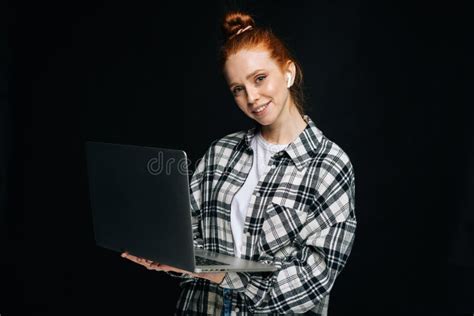 Positive Young Woman Wearing Wireless Earphones Holding Laptop Computer