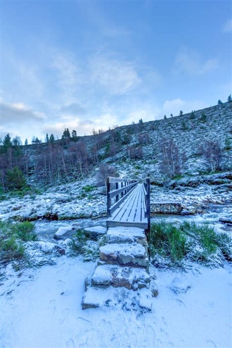 A Scenic View Of A Snowy Wooden Bridge With Stone Step Over A