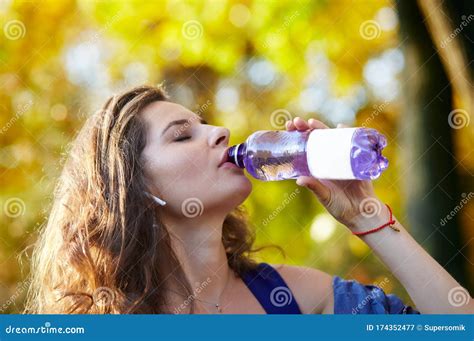 Beautiful Attractive Girl Drinks Water From A Bottle In The Park Stock