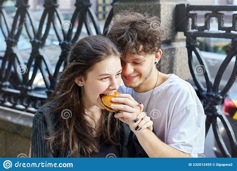 Young Guy And A Girl Are Holding Hamburgers In Their Hands The Guy