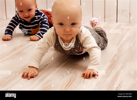 Two Babies Crawling On The Floor A Boy And A Girl The Boy Is Crying