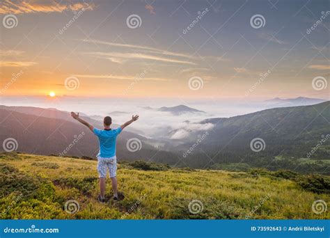 Hiker Standing On Top Of A Mountain With Raised Hands And Enjoyi Stock
