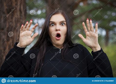 Portrait Of Frightened Beautiful Young Woman With Her Hands In Air And