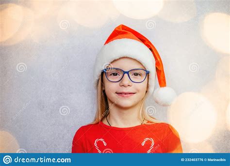 Happy Little Girl Wearing Glasses And Santa Hat During Christmas And