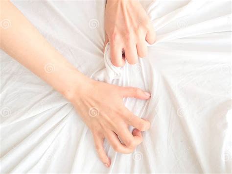 hand sign orgasm of woman on white bed hand of female pulling white sheets in ecstasy
