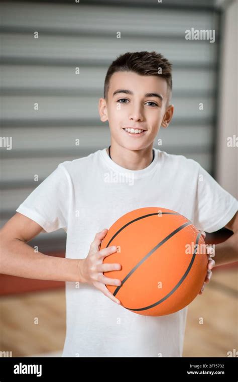 A Boy Playing Basketball In The Gym And Looking Involved Stock Photo
